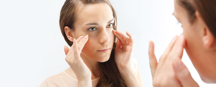 woman looking at her face in the mirror