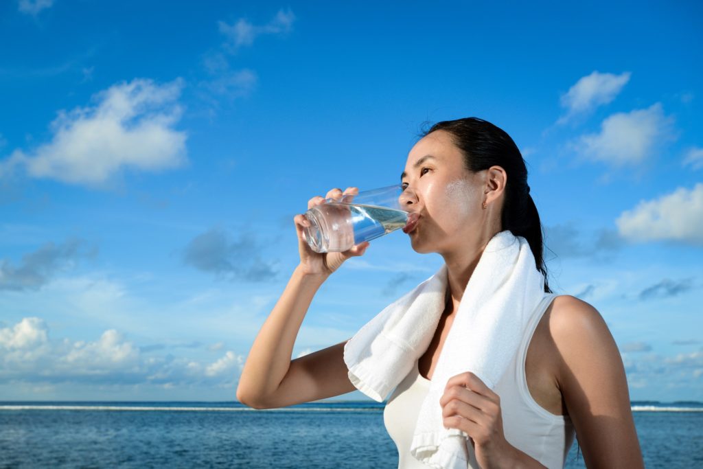 woman drinking water on the beach