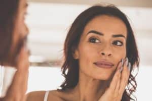 woman looking in the mirror and touching her cheek