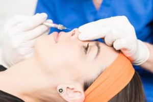 Closeup of charming woman getting a liquid rhinoplasty at a clinic.