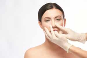 Doctor in gloves touching a woman's nose.