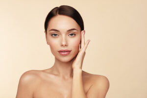 A woman posing with her hand on the side of her face, showing the results of CO2 laser resurfacing