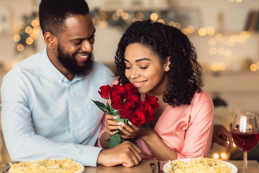 Young couple on date for valentine's day, woman smelling roses